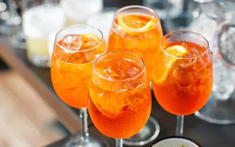 Cztery orzeźwiające drinki Aperol Spritz z lodem i plasterkami pomarańczy. Idealny aperol przepis na letnie popołudnie.
