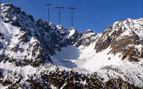 Zimowy krajobraz Tatr z zaznaczonymi szczytami Zadni, Pośredni i Skrajny. Widok na granaty szlak.