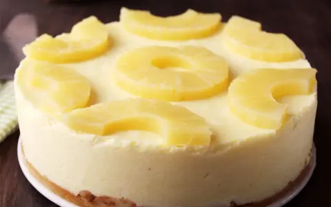 Tarta de piña cremosa, decorada con rodajas y trozos de piña fresca. ¡Un postre tropical irresistible!