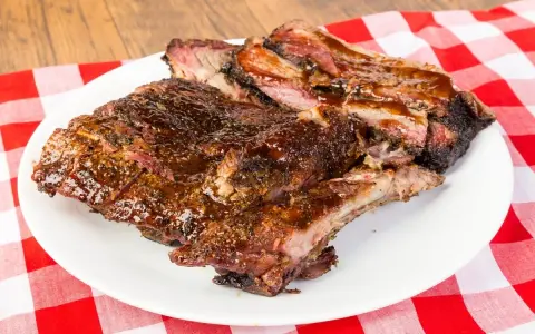 Soczyste, glazurowane żeberka BBQ na białym talerzu, idealne do jedzenia rękami. Pyszny sposób, jak jesc żeberka.