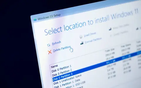 Instalator Windows 11 pokazuje opcje zarządzania partycjami. Kursor myszy wskazuje opcję "Usuń partycję", przygotowując do formatowania dysku.