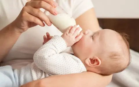 Dziecko pije mleko z butelki. Od kiedy mleko krowie zamiast modyfikowanego, maluch rośnie jak na drożdżach.