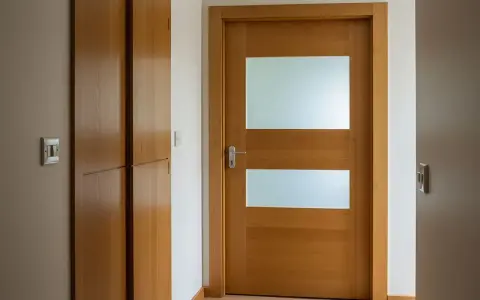 Jak przerobić stare drzwi z szybą na nowoczesne? Drewniane drzwi z dwoma matowymi przeszkleniami i minimalistycznym uchwytem.