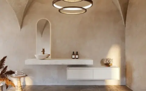 Une salle de bain nature aux murs texturés, avec un lavabo suspendu, un miroir arqué rétroéclairé et des touches végétales.