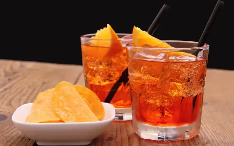 Dwa orzeźwiające drinki z pomarańczą i słone chipsy. Idealny aperitif, by rozpocząć wieczór.