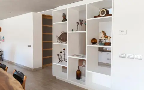Libreria in cartongesso, perfetta come divisorio per l'ingresso, con oggetti decorativi e un cavallo a dondolo.