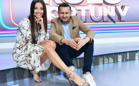 Uśmiechnięta para na planie "Koło Fortuny kto ubiera". Ona w kwiecistej sukience i sandałkach, on w marynarce i jeansach.