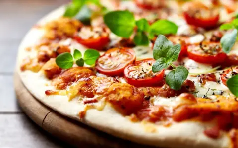 Pyszna pizza bez drożdży z pomidorkami koktajlowymi i świeżą bazylią, idealna na szybki obiad.