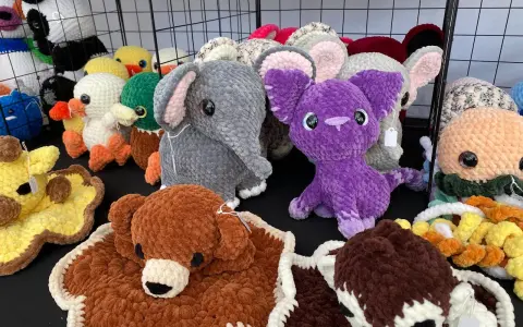 A variety of colorful, crocheted stuffed animals including elephants, ducks, a giraffe, and a purple creature.