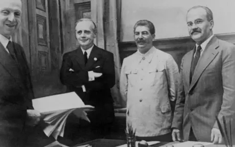 Staline et Hitler, deux figures historiques, posent ensemble. L'un tient des documents, l'autre un dossier.