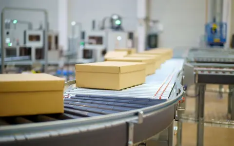 Pudełka na taśmie transportowej w magazynie ecommerce.