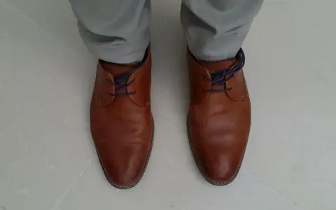 Scarpe marroni eleganti con lacci blu nascosti, un modo per allacciare le scarpe senza far vedere i lacci.
