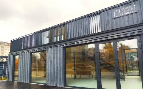 Nowoczesne centrum lokalne Kamionek, zbudowane z kontenerów. Ten innowacyjny kamionkowy materiał budowlany tworzy przestrzeń z przeszklonymi fasadami i balkonem.