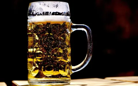 Szklany kufel z piwem, z charakterystycznymi wgłębieniami, to jeden z wielu rodzajów kufli do piwa. Piana i bąbelki dodają mu uroku.