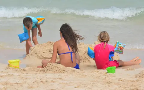 Bambini giocano sulla spiaggia, costruendo castelli di sabbia e godendosi il mare. Una giornata perfetta in una spiaggia per bambini.