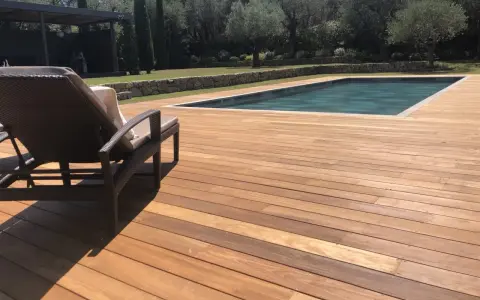 Terrasse en bois ipe vieilli, invitant à la détente au bord de la piscine sous le soleil.