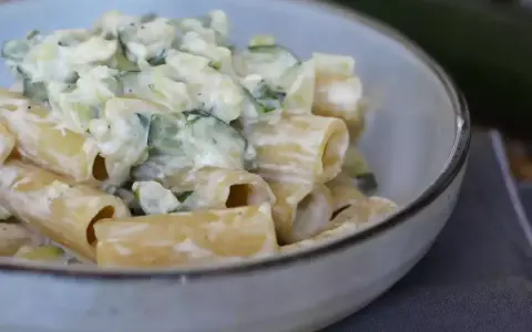 En krämig zucchini pasta i en skål, med en hel zucchini i bakgrunden.