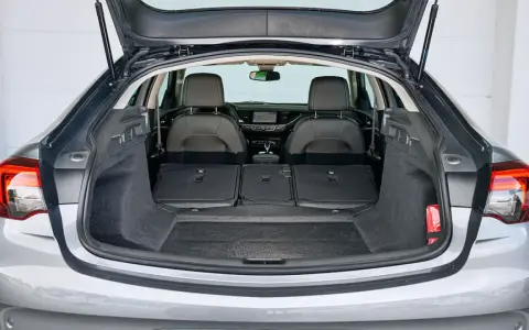 Maletero abierto de un Opel Insignia gris, mostrando asientos traseros abatidos y espacio de carga. Ideal para conocer las medidas del maletero.