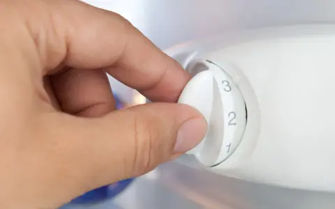 Dłoń kręci pokrętłem regulującym temperaturę w lodówce. Ustawienie na 2.