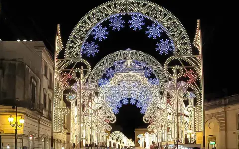 Archi luminosi illuminano la notte di Galatina per la festa di San Pietro e Paolo, creando un'atmosfera magica.