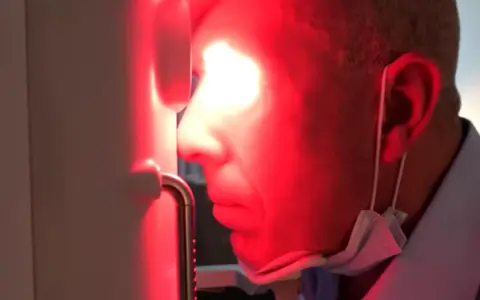 Uomo con maschera chirurgica sotto il mento, riceve fotobiomodulazione facciale. Attenzione alle fotobiomodulazione controindicazioni.