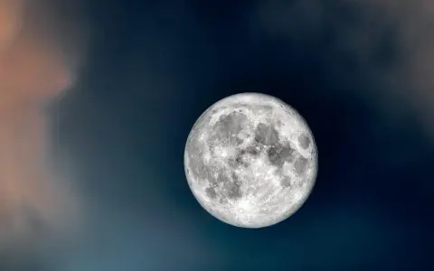 Jasny ksiezyc dzisiaj, otoczony ciemnymi chmurami, które dodają mu tajemniczości.