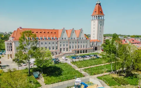Władysławowo: okazały budynek z wieżą, dawny dom rybaka, otoczony zielenią i placem zabaw.