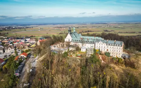 Widok z lotu ptaka na klasztor na świętej górze, otoczony lasem i miasteczkiem.