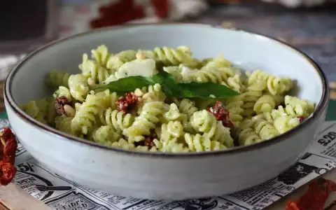 Fusilli con pesto, pomodori secchi, pinoli e basilico fresco. Un piatto di pasta con verdure colorato e saporito.