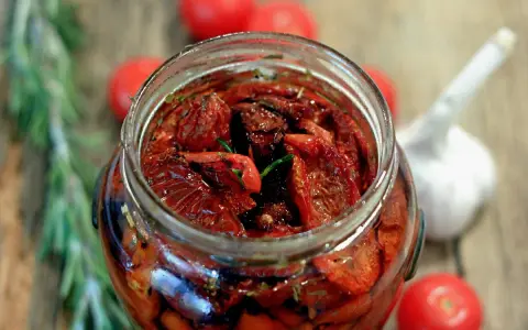 Pomodori secchi sott'olio, la ricetta della nonna. Un barattolo pieno di sole, profumato di rosmarino e aglio, pronto per insaporire ogni piatto.