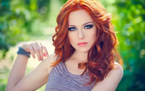 Une femme aux cheveux roux et au maquillage smoky eyes parfait, idéal pour un tuto smoky eyes débutant.