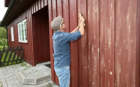 Man slipar fasaden innan målning.