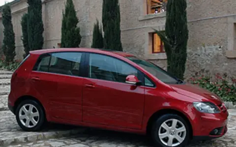 Roter VW Golf Plus mit Automatikgetriebe, der vor einem Steingebäude parkt. Mögliche Probleme mit dem Automatikgetriebe sind ein Thema.