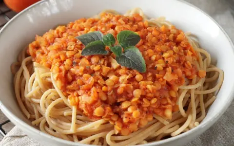 Herzhafte rote Linsen Bolognese auf Spaghetti, garniert mit frischen Kräutern. Ein köstliches und gesundes Gericht.