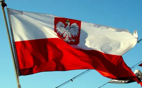 Polska bandera z orłem na tle błękitnego nieba. To symbol dumy narodowej, który powiewa na wietrze.
