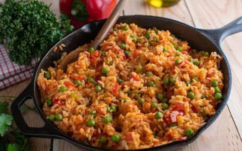 Djuvec Reis mit Erbsen und Paprika in einer Gusseisenpfanne, bereit zum Servieren.