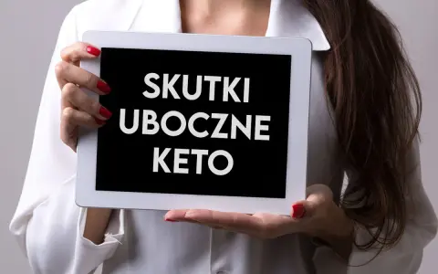 Kobieta trzyma tablet z napisem "SKUTKI UBOCZNE KETO". Warto wiedzieć, jakie są objawy problemów z jelitami przy tej diecie.