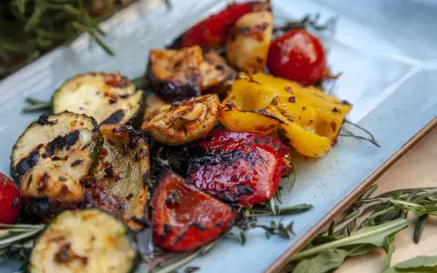 Gegrilltes Gemüse wie Zucchini, Paprika und Tomaten, garniert mit Rosmarin. Perfekt für Ihre nächsten BBQ Rezepte!
