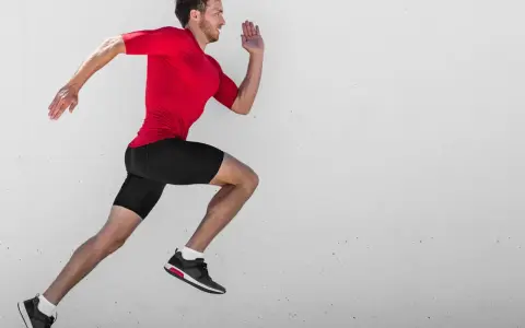 Ein Mann in rotem Shirt und schwarzen Shorts läuft mit hoher Kadenz gegen eine Betonwand.