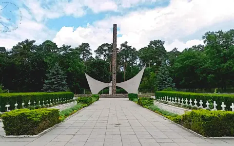 Pomnik i rzędy białych krzyży na cmentarzu w Siekierkach.