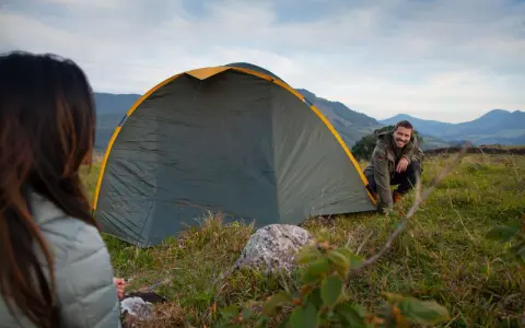 Mann und Frau biwakieren in Deutschland. Sie bauen ein Zelt in den Bergen auf, die Landschaft ist wunderschön.