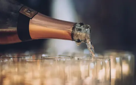 En flaska hälls upp i glas, det ser ut att bli gott bubbel.