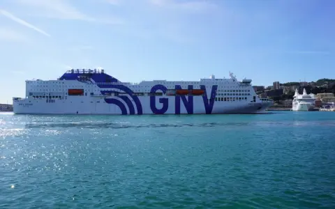 Ogromny prom GNV Orion czeka na pasażerów, by zabrać ich w podróż na Sycylię. W tle widać port i wzgórza.