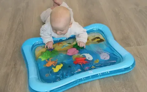 Niemowlę bawi się na macie wodnej dla niemowląt z morskimi stworzeniami.