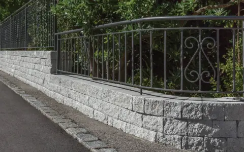 Muro in pietra grigia con ringhiera in ferro battuto, un'ottima idea per muri di recinzione moderni ed eleganti.