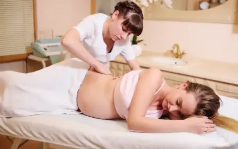Relaksacyjny masaż w ciąży dla przyszłej mamy. Terapeuta delikatnie masuje plecy, przynosząc ulgę.