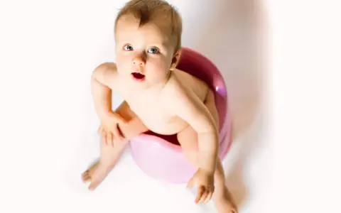 Bambino seduto sul vasino rosa, con espressione sorpresa. Attenzione alla cistite nei bambini.