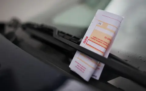 Ein Strafzettel unter dem Scheibenwischer. Parken ohne Parkschein kostet Geld und Ärger.