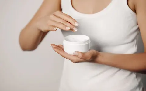 Manos aplicando crema para suavizar la piel y tratar la queratosis pilaris.