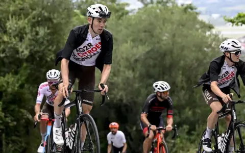 Radfahrer im Rennen bei der Dauphiné Rundfahrt. Ein Fahrer in weißem Trikot mit "AG2R CITROEN" Aufschrift fährt bergauf.